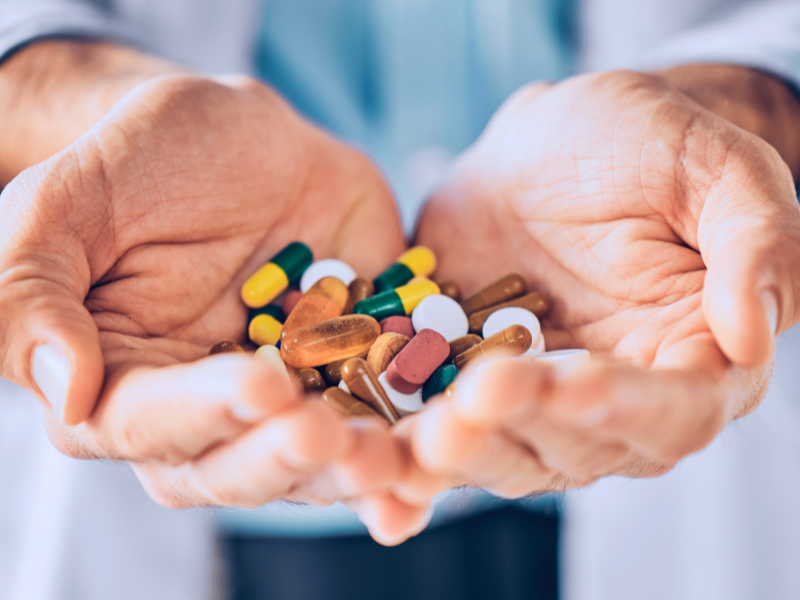 Médico segurando medicamentos nas duas mãos.